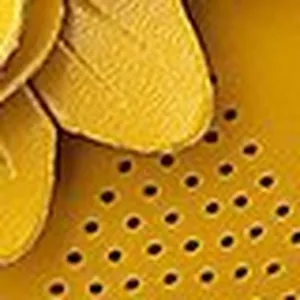 Makro-Detail von gelber Blumendekoration und Lochmuster auf Damen-Keilsandalen