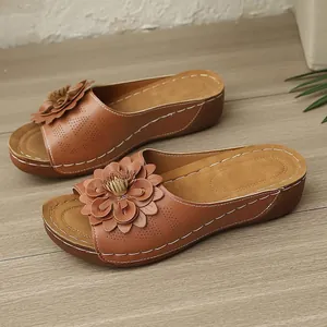 Detailansicht brauner Keilsandaletten mit Blumendekor und Lochmuster-Verzierung.