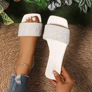 Dettaglio di eleganti sandali flat a punta quadrata con perle bianche e strass.