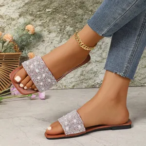 Dettaglio di ciabatte piatte da donna con punta quadrata, perle e strass luccicanti