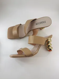 Detailansicht stilvoller brauner Sandalen mit einzigartigen goldenen Kugelabsätzen