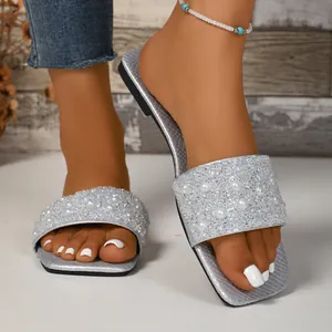 Dettaglio di ciabatte argento con strass luccicanti e decorazioni di perle bianche.