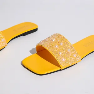 Primo piano di ciabatte gialle con eleganti decorazioni di perle e perline di strass