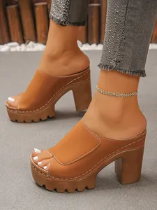Detail view of stylish tan platform mules with chunky heels and white contrast stitching.