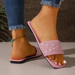 Vista dettagliata dei sandali bassi rosa con cinturini decorati con perle e strass.