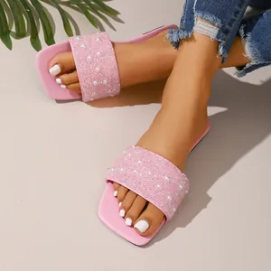 Vista dettagliata dei sandali piatti rosa da donna con eleganti cinturini in perle e strass