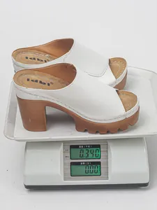 Detail shot showing the weight of white platform high-heeled sandals on a scale