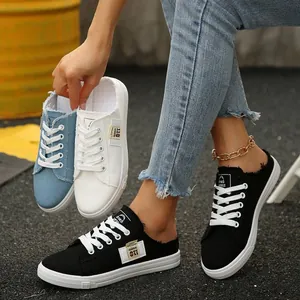 Detailweergave van dames canvas mules met rafelranden in zwart, wit en denimblauw.