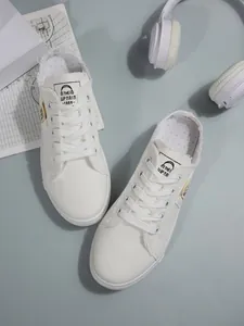 Gedetailleerde bovenaanzicht van witte canvas instappers met gerafelde randen.