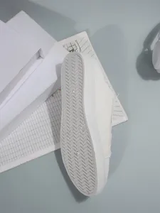 Gedetailleerd overzicht van de antislip rubberen zool op witte dames canvas instapschoenen