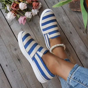Detailweergave van blauw en wit gestreepte canvas instapschoenen voor dames op houten vloer