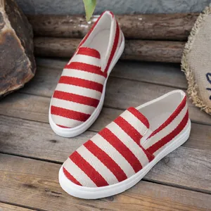Gedetailleerde weergave van rood-wit gestreepte canvas instappers op houten planken.