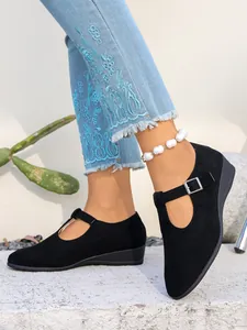 Vista dettagliata delle scarpe con zeppa in pelle scamosciata nera con cinturino