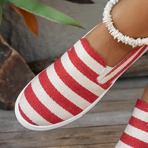 Gedetailleerde macro-opname van rood-wit gestreepte canvas loafers op hout