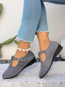 Primo piano di scarpe con zeppa in camoscio grigio con cinturino a fibbia regolabile