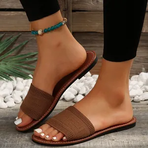 Detalle de sandalias planas de punto marrón para mujer en un entorno de jardín de verano