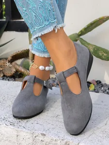 Vista dettagliata di scarpe con zeppa Mary Jane in camoscio grigio indossate da modella