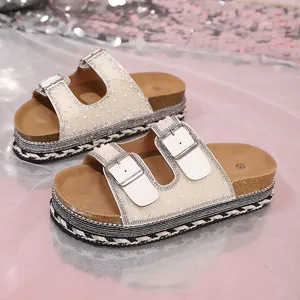 Close-up of beige platform sandals featuring rhinestone buckles and pearl accents.