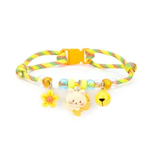 Detail view of colorful woven cat collar with cartoon kitten, bell, and flower charms