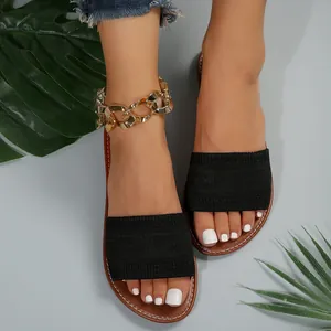 Vista detallada de las sandalias planas para mujer con tira de punto negro y suela marrón.