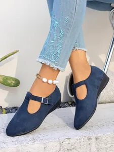 Dettaglio elegante di scarpe con zeppa in camoscio blu con cinturino a T e fibbia