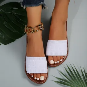 Primer plano de las sandalias planas de punto blanco para mujer con patrón sutil.