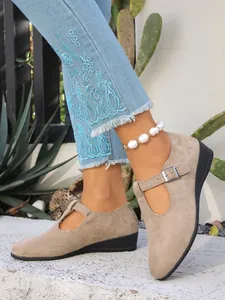 Dettaglio delle scarpe Mary Jane con zeppa in pelle scamosciata taupe e cinturino
