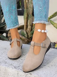 Primo piano di scarpe con zeppa Mary Jane in pelle scamosciata beige con jeans