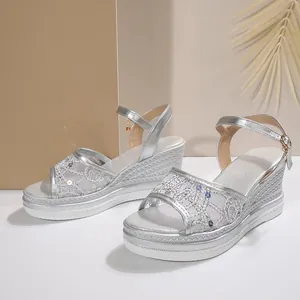Détail de sandales compensées argentées avec maille pailletée et bride à boucle.