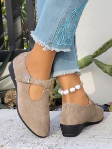Dettaglio di scarpe con zeppa in pelle scamosciata con fibbia e jeans alla moda.