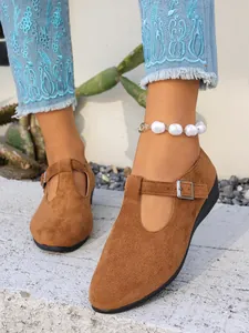 Dettaglio ravvicinato di scarpe Mary Jane in camoscio marrone con cinturino a T