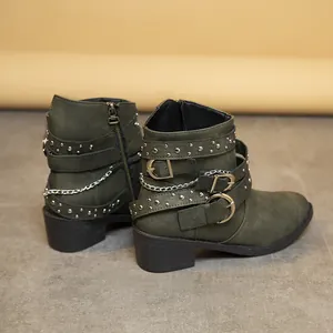 Vista detallada de botas punk verde oliva con remaches, hebillas y cadenas de metal.