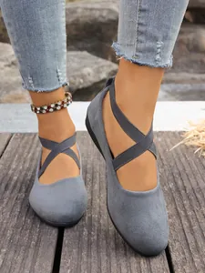 Primo piano di ballerine in camoscio grigio con elastici incrociati sui piedi di una modella.