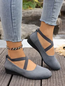 Vista dettagliata di scarpe con zeppa in camoscio grigio e cinturini elastici incrociati
