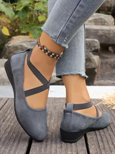 Primo piano di eleganti scarpe con zeppa in camoscio grigio con cinturini elastici incrociati