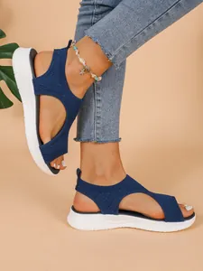 Nahaufnahme von blauen Sport-Sandalen für Damen mit dicker weißer Sohle am Fuß.
