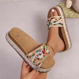 Detalle de sandalias bohemias con plataforma, cuentas de colores y dije de insecto