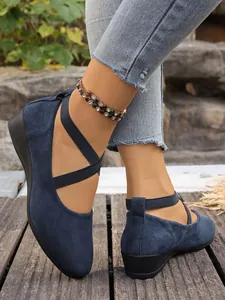 Dettaglio di scarpe con zeppa in camoscio blu navy con cinturini elastici incrociati.