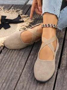 Dettaglio scarpe in camoscio beige da donna con cinturini elastici incrociati