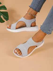 Detaillierte Nahaufnahme grauer Mesh-Strick-Sportsandalen mit dicken weißen Sohlen am Fuß