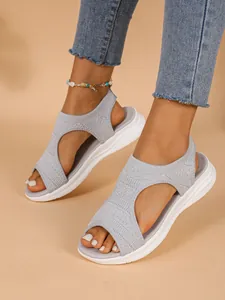 Nahaufnahme grauer Fly-Knit Keilsandalen mit atmungsaktivem Mesh und weißer Sohle.