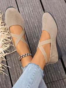 Dettaglio di scarpe con zeppa in pelle scamosciata e cinturini elastici incrociati