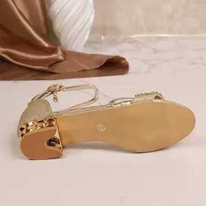 Nahaufnahme der Sohle und des Absatzes von goldenen Strass-Sandalen mit Blockabsatz
