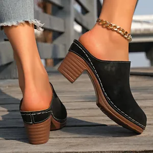 Vue détaillée de mules noires en daim à talons avec coutures blanches contrastées