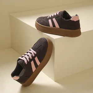 Close-up of retro platform sneakers in brown suede with pink laces and accents.