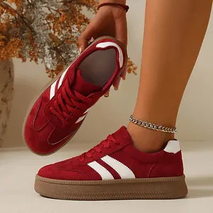Macro detail view showing red suede platform sneakers with white stripes and gum sole