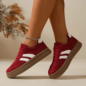 Detailed view of women's burgundy suede retro sneakers with classic white side stripes.