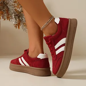 Close-up of red suede German trainer sneakers with iconic white stripes on the side