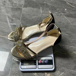 Elegante goldene Sandalen mit Strasssteinen und Blockabsatz auf einer digitalen Waage