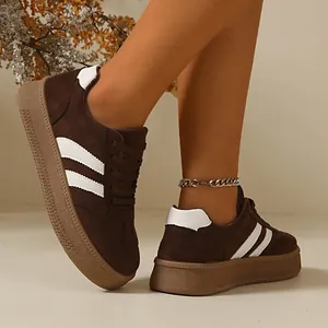 Close-up of women's brown suede retro sneakers with thick gum soles and white stripes